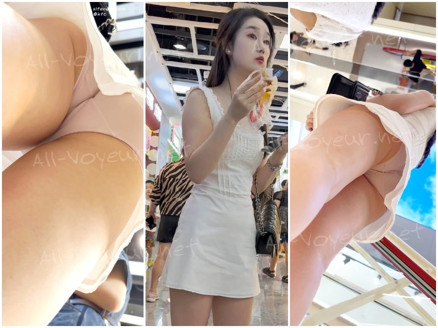 サンドドレスを着た若い女性が一人で買い物をしながらスナックを食べています。彼女のピンクの薄い裏地は少し透けていて、低い角度で CD をかけています。