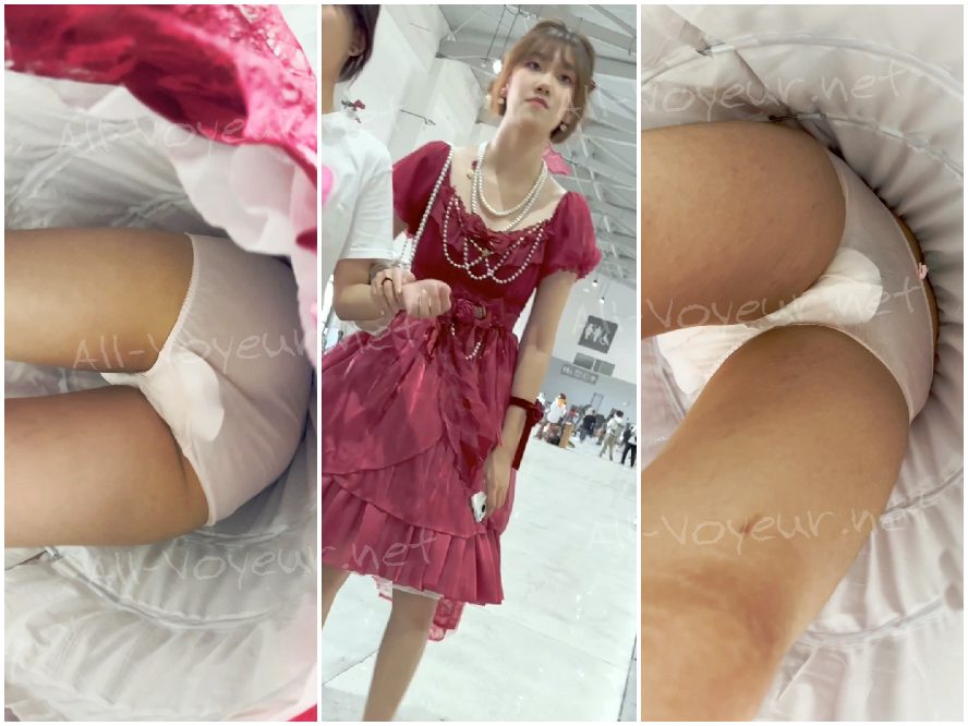 母親と幼い弟と一緒に買い物に出かけている若い学生。彼女は透け感のある赤いロングドレスを身にまとっており、その下には白い使い捨ての下着が透けて見えている。